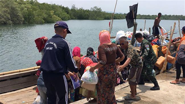 This handout photo released and taken by the Royal Thai Army on April 1, 2018, shows a member of the Royal Thai Navy rescue team assisting Rohingya refugees to board their wooden boat after a brief stop on an island in Krabi province. (Photo by AFP)
