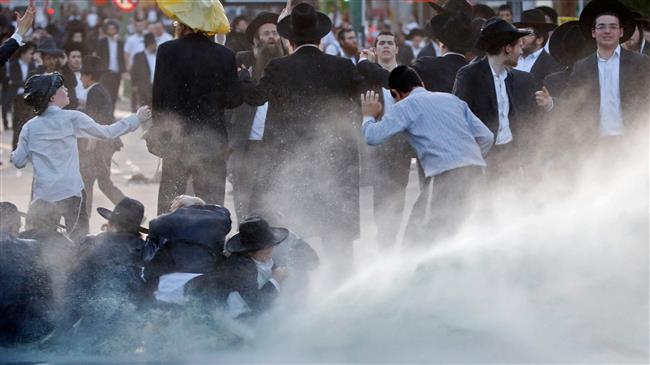 Israeli forces use water cannons against protesters blocking the road in a demonstration against conscription in the Israeli city of Bnei Brak near Tel Aviv, March 22, 2018. (Photo by AFP)
