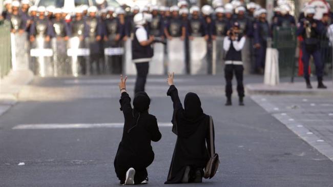 The file photo shows anti-government protesters kneel in the street and gesture toward riot police in Bahrain