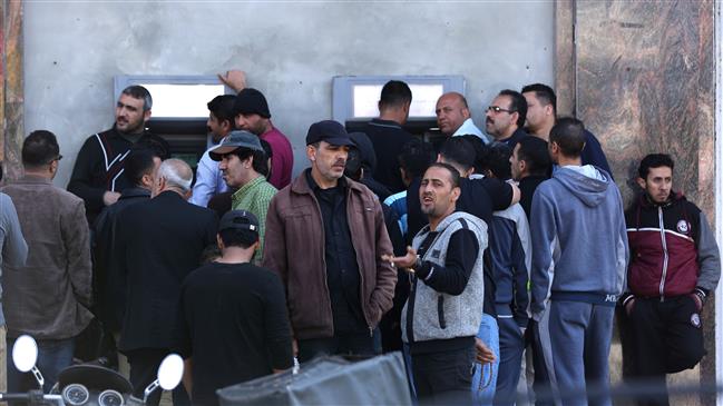 Palestinian employees queue outside a cash machine outside the Bank of Palestine as they wait to withdraw their salaries in Gaza City on April 9, 2018. (Photo by AFP)
