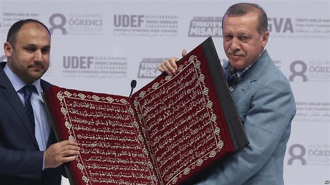 Turkey’s President Recep Tayyip Erdogan (R) receives a copy of the Qur’an at an international students’ meeting in Istanbul, Turkey, on May 16, 2015. (Photo by AP)
