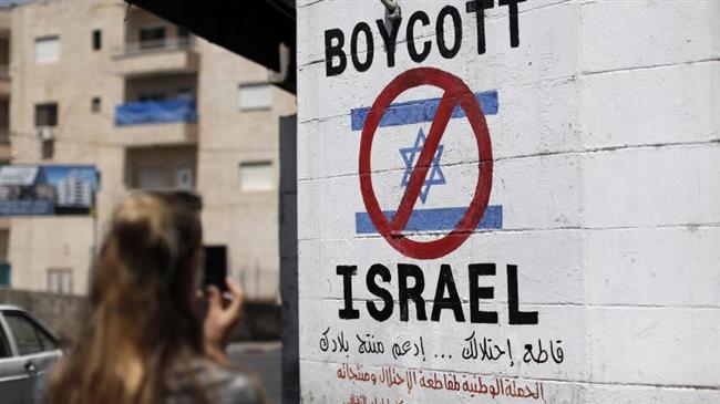 A tourist photographs a sign painted on a wall in the West Bank town of Bethlehem on June 5, 2015, calling to boycott Israeli products coming from Israeli settlements. (Photo by AFP)
