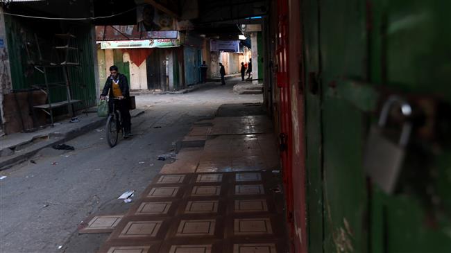 A man rides a bicycle past closed shops during a general strike to mourn Palestinians who were killed during protests against US