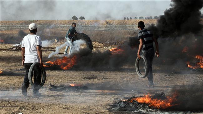 Palestinian demonstrators burn tires during clashes with Israeli forces along the border with the Gaza strip east of Khan Yunis on May 18, 2018. (Photo by AFP)
