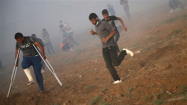 Palestinians run for cover from tear gas shot by Isreali forces during a demonstration along the Gaza Strip’s border, May 25, 2018. (Photo by AFP)
