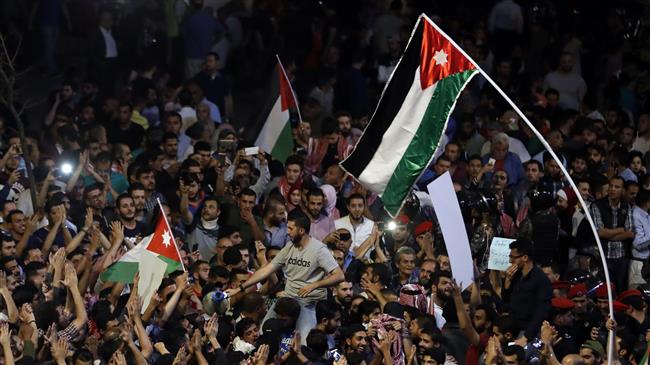 Jordanian demonstrators wave the national flags during a protest near the prime minister
