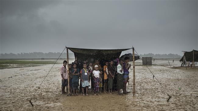 In this photo taken on October 06, 2017, Rohingya Muslim refugees take shelter from the rain during a food distribution at Nayapara refugee camp in Bangladesh. (Photo by AFP)
