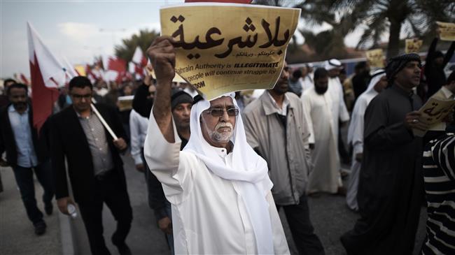 The file photo shows a Bahraini man holding up a placard reading, "Your government and your parliament are without legitimacy" during an anti-regime protest in the village of Jannusan, west of the Manama. (Photo by AFP)
