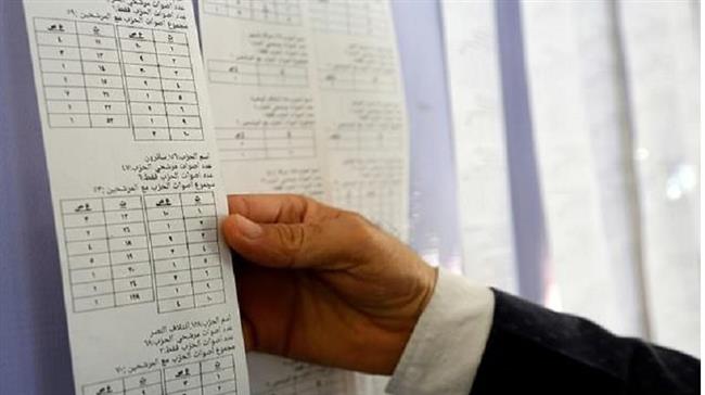 An Iraqi electoral commission official examines electronic counting machine print-outs in Najaf on May 13, 2018 . (Photo by AFP)
