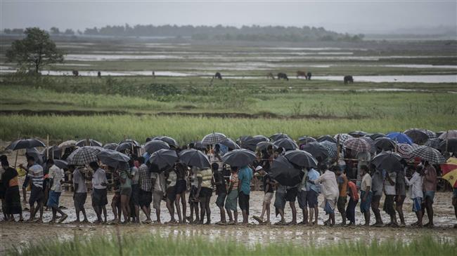 In this file photo taken on October 06, 2017, Rohingya Muslim refugees wait in line under the rain during a food distribution at Nayapara refugee camp in Bangladesh