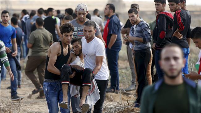 Palestinians carry a wounded protester who was shot by Israeli troops during clashes near the border
