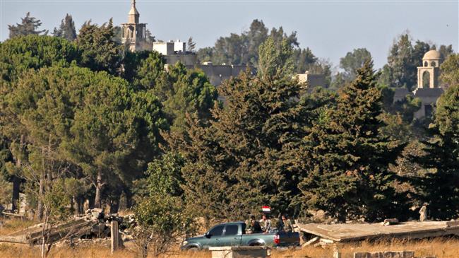 A picture taken on July 26, 2018, near the Ein Zivan settlement in the Israeli-occupied Golan Heights, shows members of the Syrian security forces carrying a national flag across the border as government forces retake their positions from the militants. (AFP photo)
