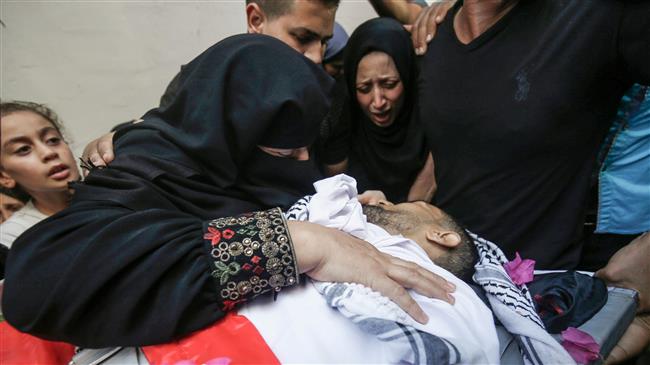 The mother (C-L) of 21-year-old Palestinian volunteer medic, Abdullah al-Qatati, mourns over his body during his funeral in Rafah in the southern Gaza Strip on August 11, 2018, after he succumbed to gunshot wounds he suffered the day before while trying to help wounded protesters along the border fence separating the Gaza Strip from the occupied territories. (Photo by AFP)
