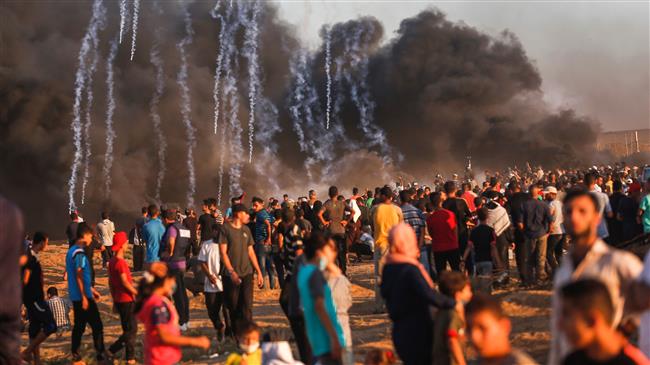 Palestinian protesters watch as tear gas grenades fired by Israeli forces fall during clashes following a demonstration along the border between the besieged Gaza Strip and occupied territories on September 7, 2018. (Photo by AFP)
