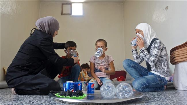A Syrian woman tries an improvised gas mask on family members in her home in Idlib Province on September 12, 2018 as part of preparations for any upcoming chemical attack. (Photo by AFP)
