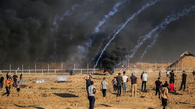 Palestinian protesters stand by as tear gas canisters fired by Israeli forces fall amidst them in clashes during a demonstration along the Israeli fence east of Gaza City on September 21, 2018. (AFP)
