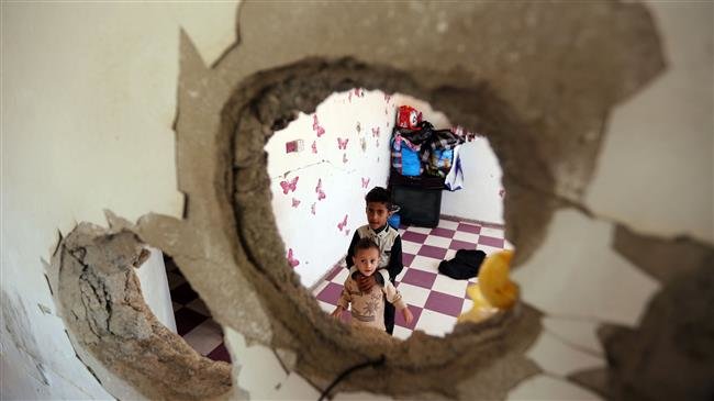 Displaced Yemeni children from Hudayda province living with their family in a house destroyed during the Saudi-led war against their country are seen through a hole in a wall in the province of Taiz, on September 30, 2018. (Photo by AFP)
