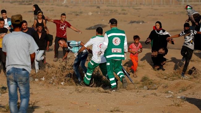 Palestinian paramedics help a protester at the border of the besieged Gaza Strip with the occupied territories, east of Gaza city, on October 12, 2018. (Photo by AFP)
