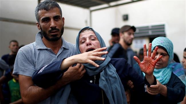 The mother of a Palestinian, who was killed in an Israeli airstrike, reacts as her hand is stained with her child