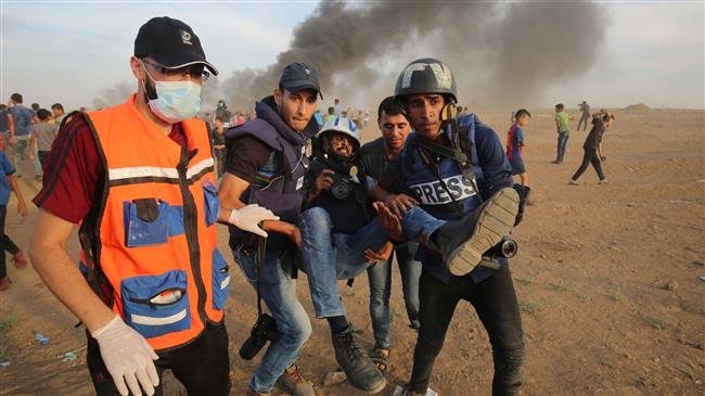 Palestinian paramedics and journalists carry a wounded fellow journalist during clashes with Israeli forces along the so-called border fence between the Gaza Strip and the occupied territories on October 5, 2018. (Photo by AFP)
