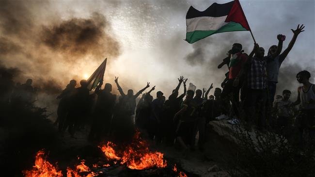Palestinian protesters wave national flags as they stand near burning tyres during a demonstration on the beach near the maritime border with Israel, in the northern Gaza Strip, on October 22, 2018. (AFP)
