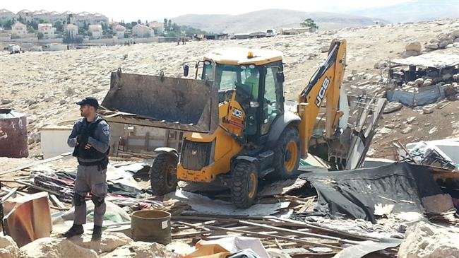 This file photo shows Israeli regime forces guarding a British company JCB