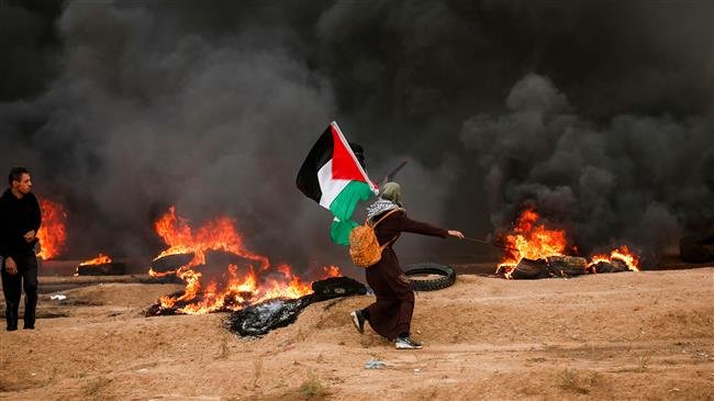 A female Palestinian protester runs with a Palestinian flag during clashes following a demonstration near the fence area separating the occupied territories from Gaza City, October 26, 2018. (Photo by AFP)
