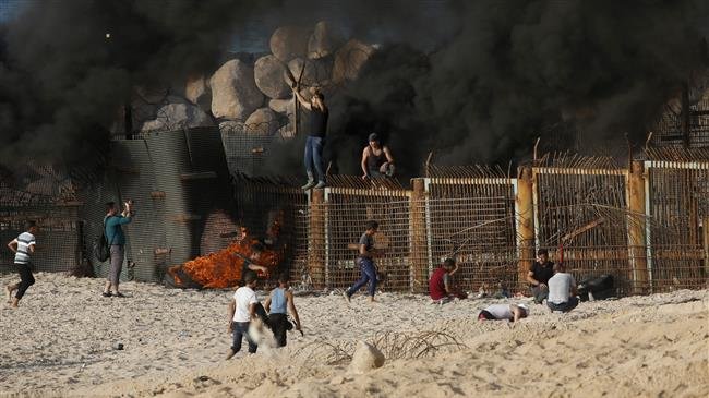 Palestinian protesters climb a fence separating them from Israeli security forces during demonstration on the beach near the maritime border with the Israeli-occupied territories, in the northern Gaza Strip, on October 15, 2018. (Photo by AFP)
