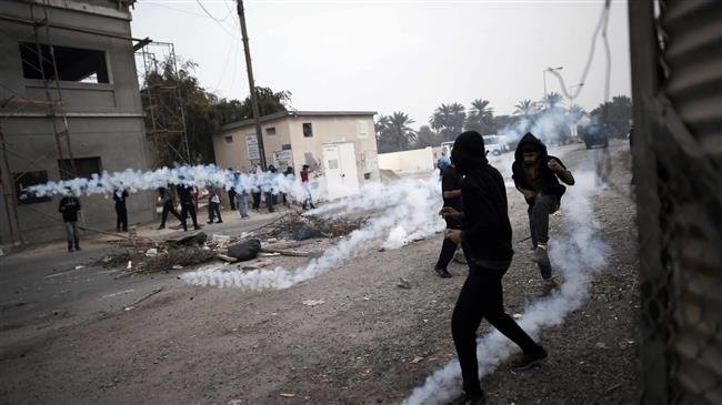 This picture, taken on February 13, 2015, shows Bahraini protesters taking cover from tear gas during clashes with police following a demonstration. (By AFP)
