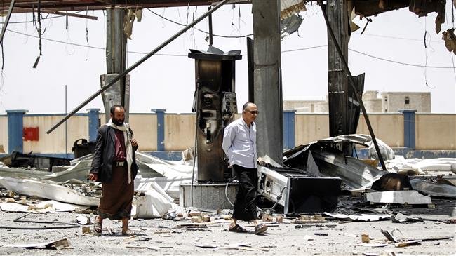 Yemeni men walk through the rubble and debris of a destroyed petrol station that was hit by a Saudi airstrike in the capital Sana’a on May 27, 2018. (By AFP)
