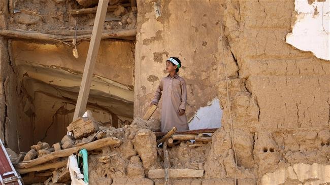 A boy stands on the rubble of a house destroyed during the conflict in the northwestern city of Sa